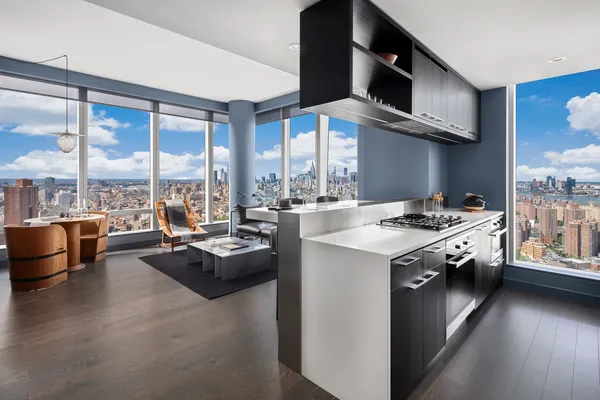 a kitchen with stainless steel appliances granite countertop a stove and a view of living room with a large window