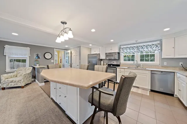 a large white kitchen with a refrigerator a stove a sink a dining table and chairs