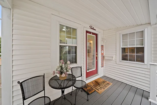 a balcony with table and chairs and potted plants