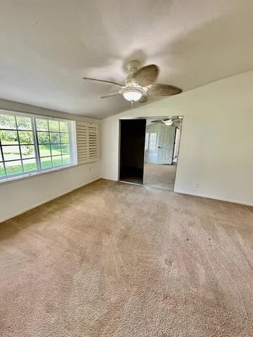 an empty room with windows and ceiling fan