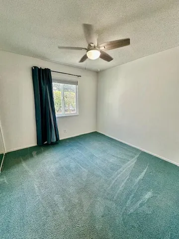 an empty room with windows and fan