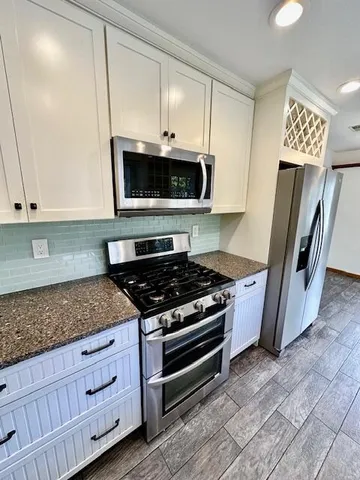 a kitchen with granite countertop white cabinets and stainless steel appliances