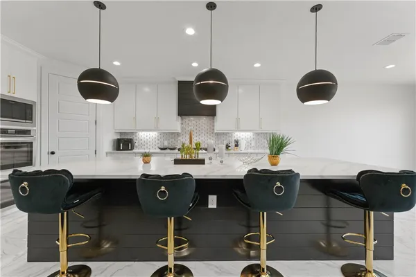 a kitchen with stainless steel appliances granite countertop a dining table chairs and white cabinets