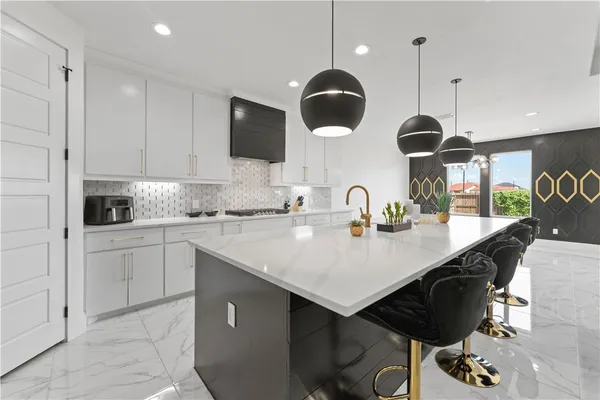a kitchen with stainless steel appliances a sink a stove a kitchen island with chairs and white cabinets
