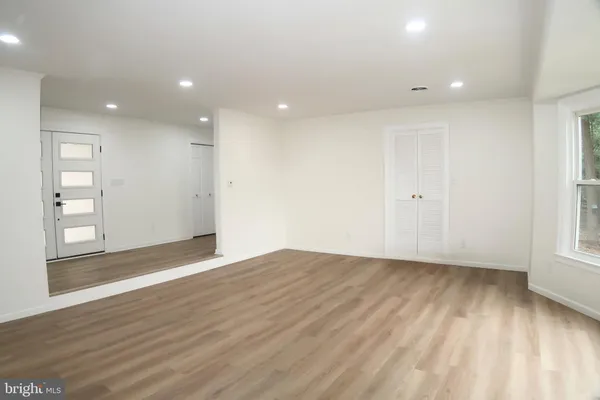 a view of a hallway with wooden floor and a bathroom