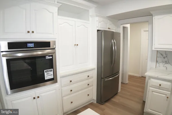 a kitchen with granite countertop a stove a sink and white cabinets with wooden floor