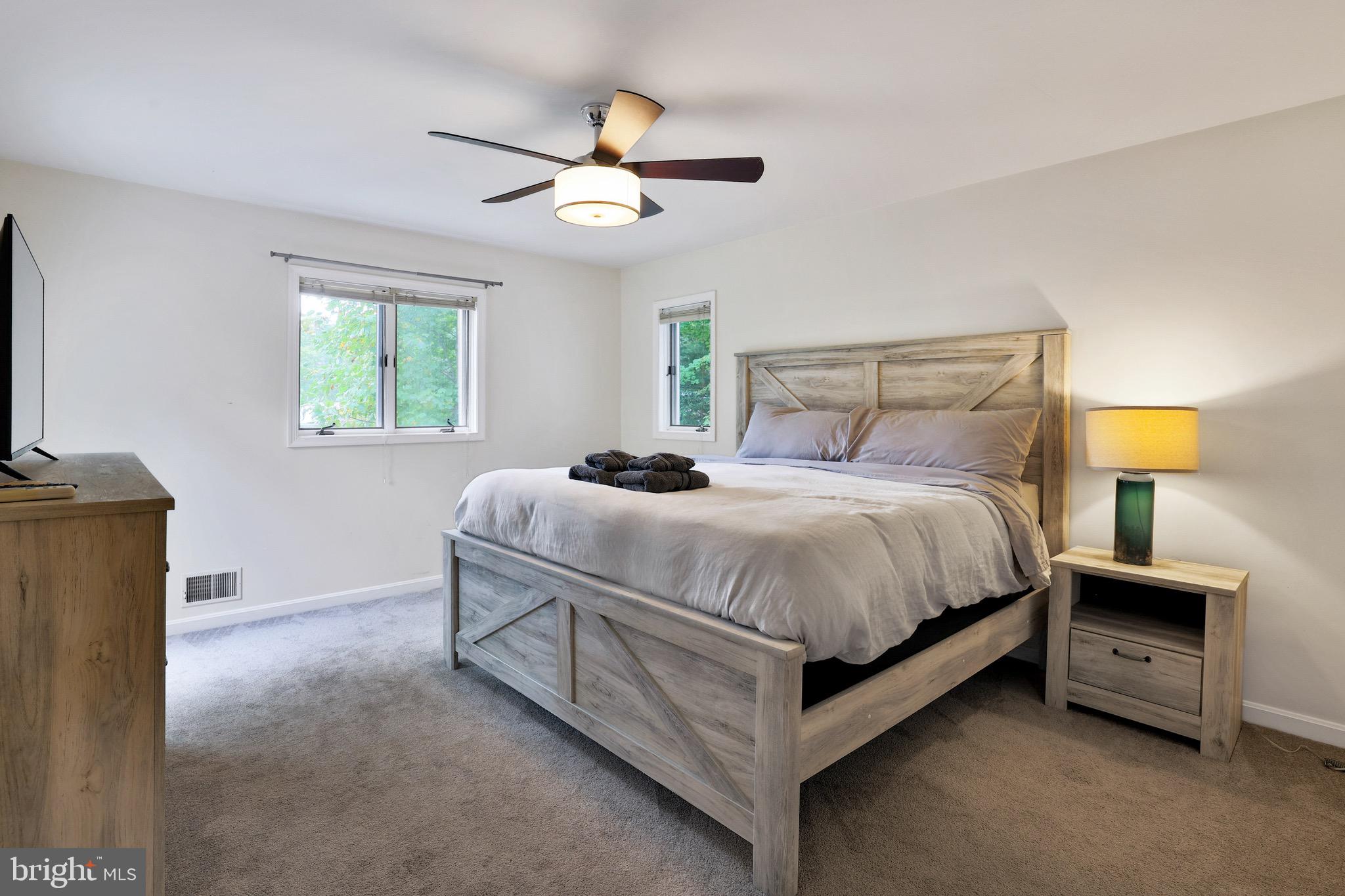 920 Old Annapolis Neck Road Annapolis, MD 21403 - Photo 24 of 58 a bedroom with a bed a lamp on dresser and a chandelier