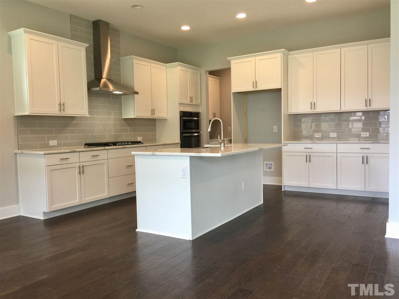 5248 Aleppo Lane, Unit 47 Raleigh, NC 27613 - Photo 7 of 19 a kitchen with stainless steel appliances granite countertop a stove top oven a sink and white cabinets with wooden floor