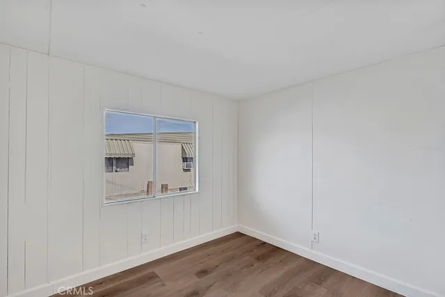 an empty room with wooden floor and mirror