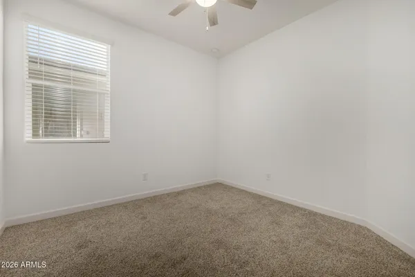 an empty room with a chandelier fan and window