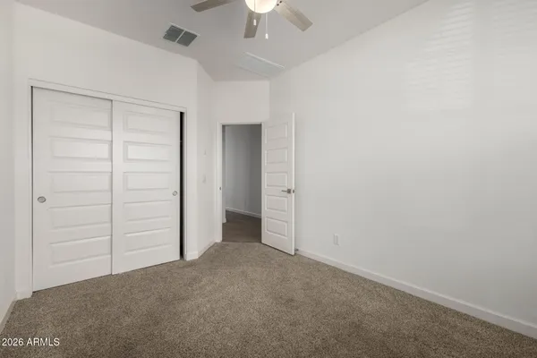 an empty room with a chandelier fan and windows