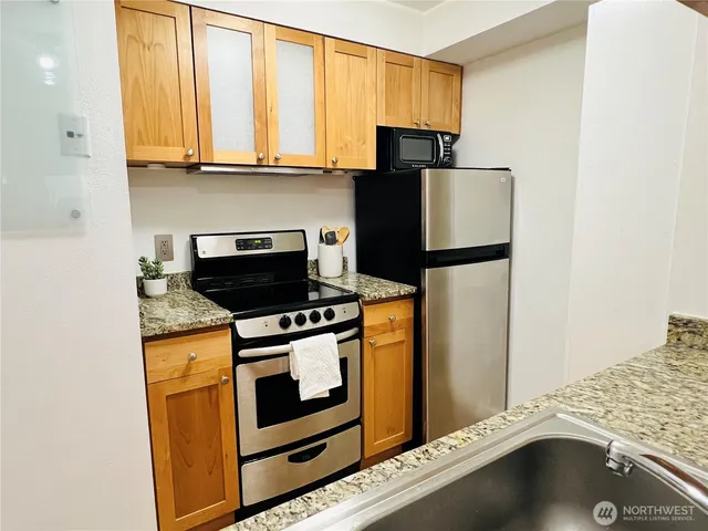 a kitchen with stainless steel appliances granite countertop a stove a microwave and a refrigerator