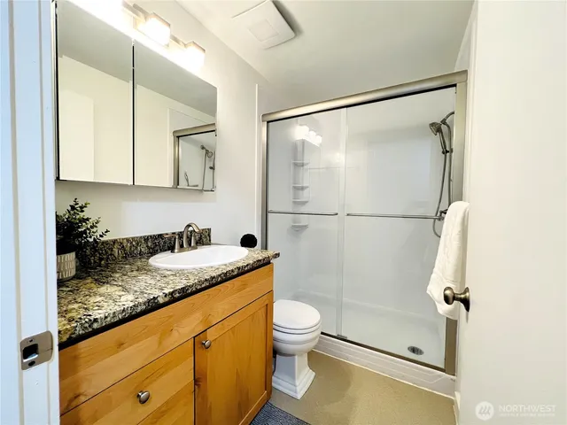 a bathroom with a granite countertop sink mirror vanity and toilet