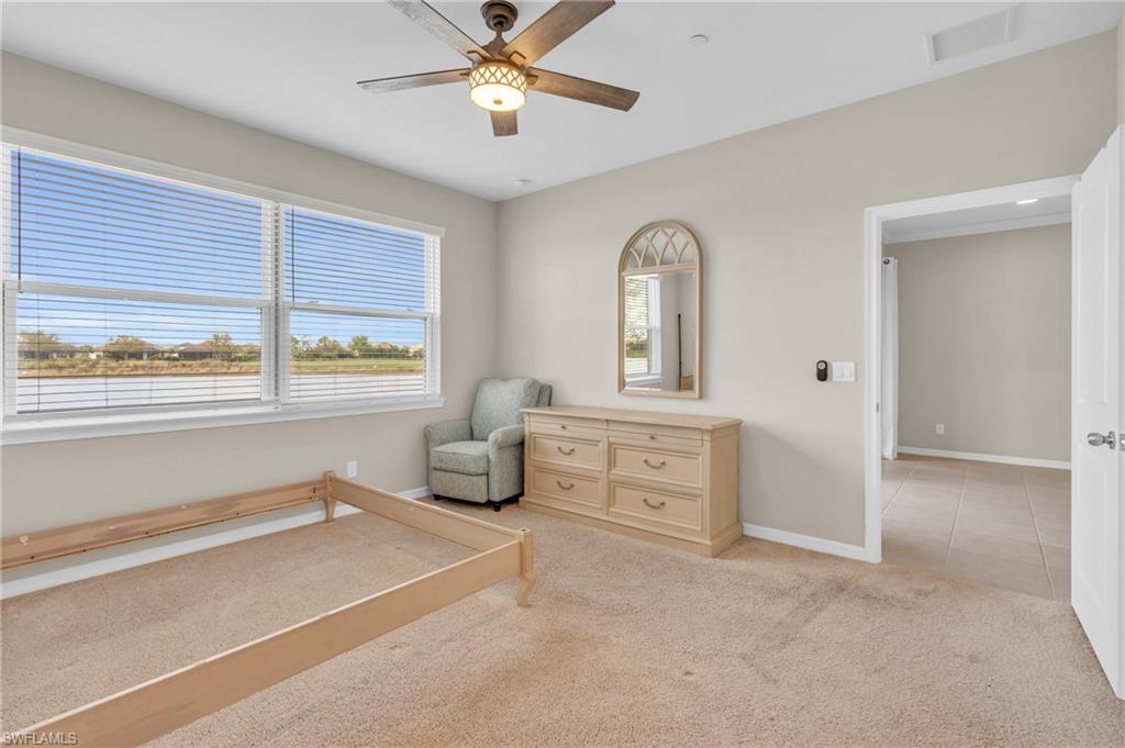 9385 Pocida Court, Unit 101 Naples, FL 34119 - Photo 14 of 26 a spacious bedroom with a bed and a chandelier