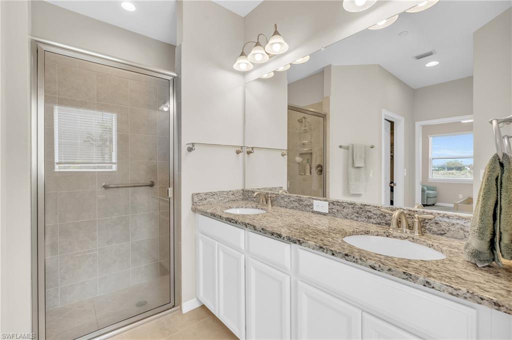 9385 Pocida Court, Unit 101 Naples, FL 34119 - Photo 16 of 26 a bathroom with a granite countertop sink a mirror and a shower