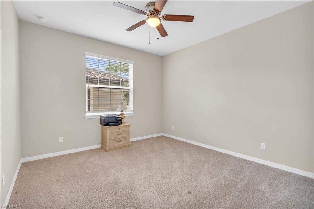 9385 Pocida Court, Unit 101 Naples, FL 34119 - Photo 18 of 26 an empty room with chandelier fan and windows