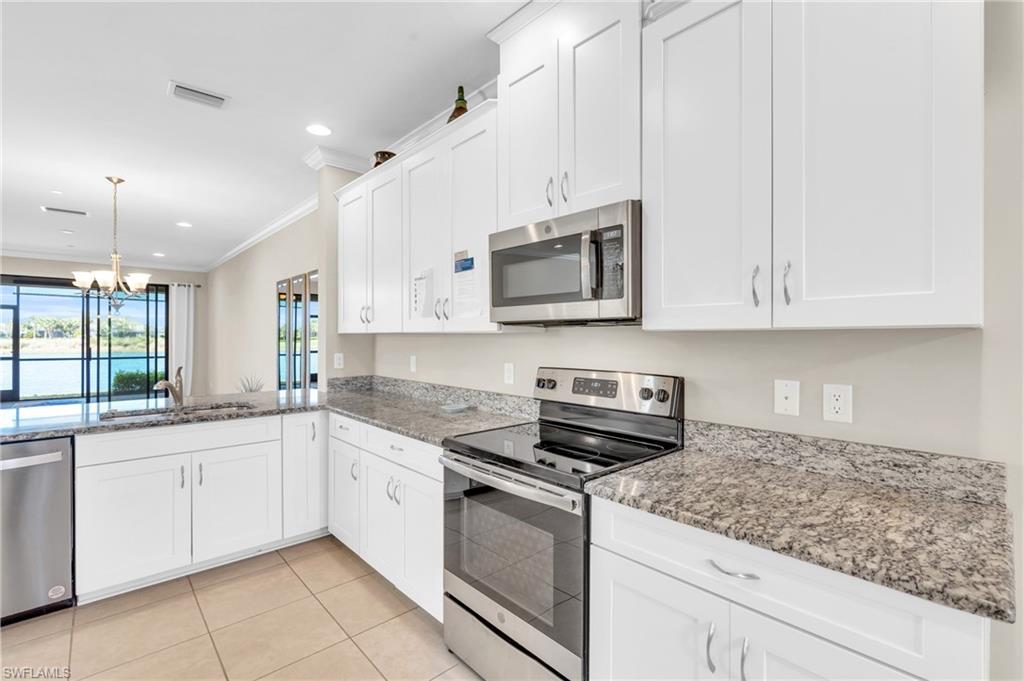 9385 Pocida Court, Unit 101 Naples, FL 34119 - Photo 9 of 26 a kitchen with stainless steel appliances granite countertop white cabinets a sink and dishwasher
