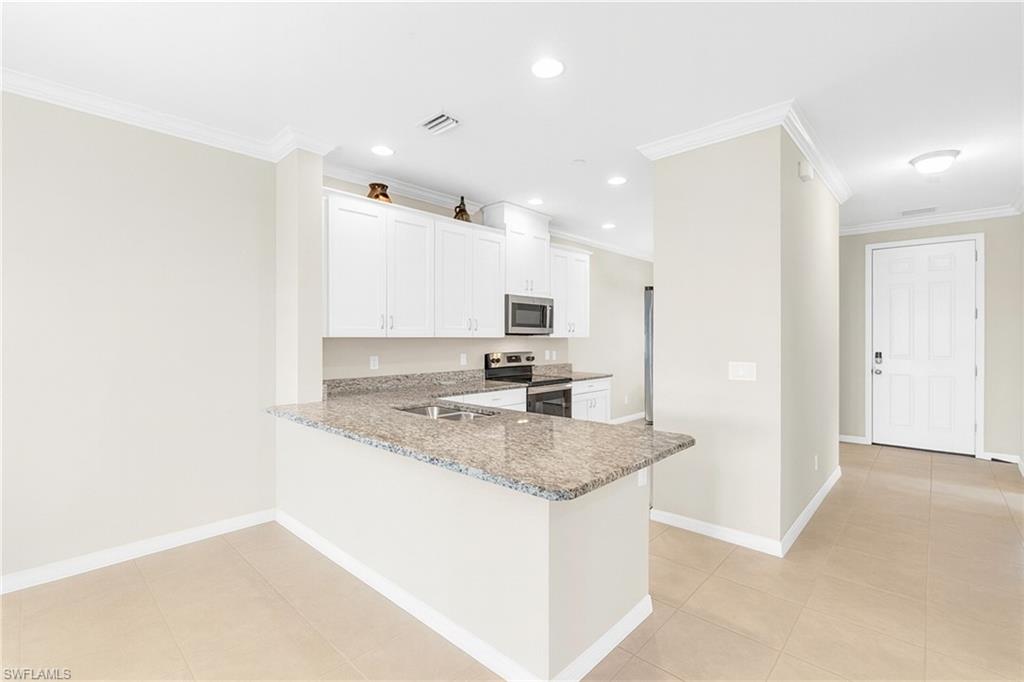 9385 Pocida Court, Unit 101 Naples, FL 34119 - Photo 10 of 26 a kitchen with kitchen island granite countertop a sink and refrigerator
