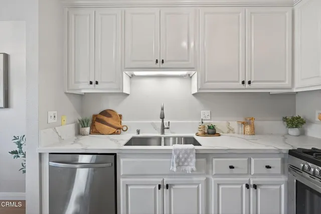 a kitchen with granite countertop white cabinets and stainless steel appliances