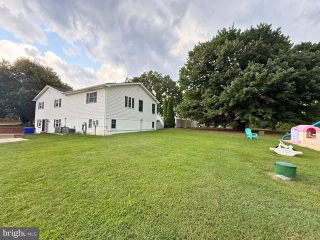 a view of a white house in a big yard with wooden fence
