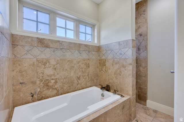 650 East Center Street Alpine, UT 84004 - Photo 18 of 38 New Built-in soaking tub surrounded by natural stone tiling with entrance to doorless shower