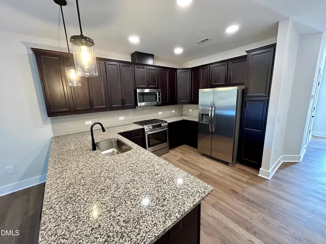 a kitchen with stainless steel appliances granite countertop a refrigerator a sink a stove a microwave and island