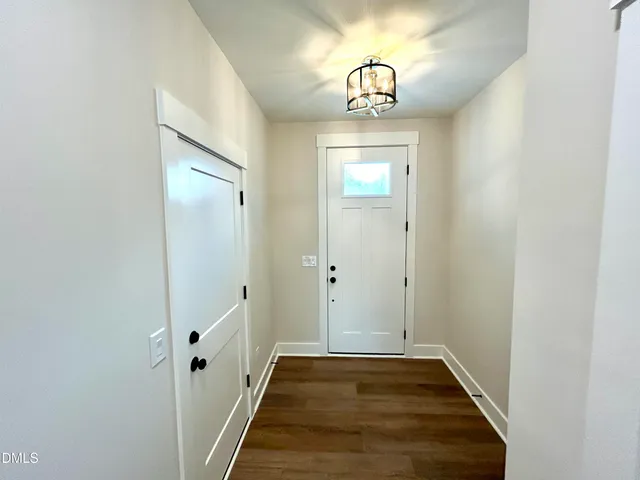 a view of a hallway with wooden floor and chandelier