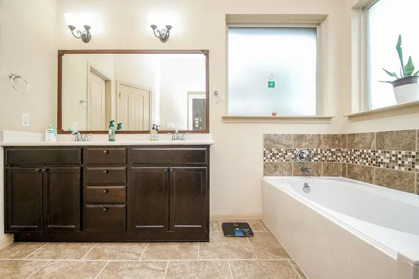a bathroom with a tub a sink and mirror