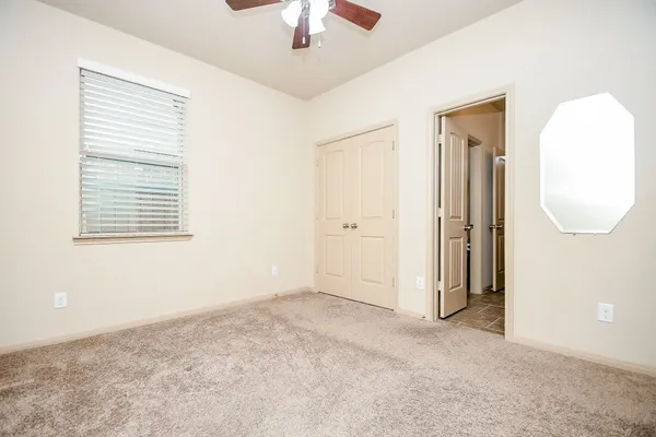 an empty room with a window and a chandelier fan