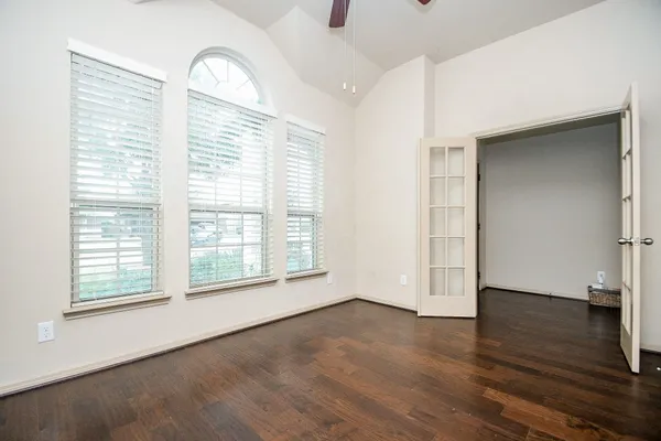 an empty room with wooden floor and windows