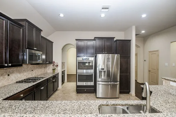 a kitchen with stainless steel appliances granite countertop a refrigerator and a stove