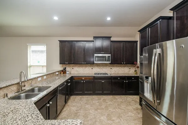 a large kitchen with kitchen island granite countertop a sink and a refrigerator