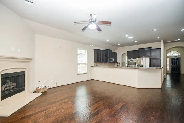 a view of a kitchen with furniture a ceiling fan and wooden floor