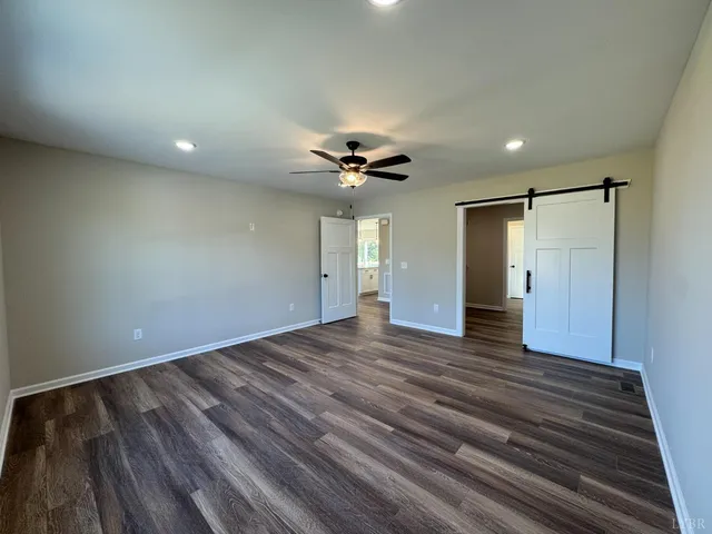 a view of an empty room and a ceiling fan wooden floor