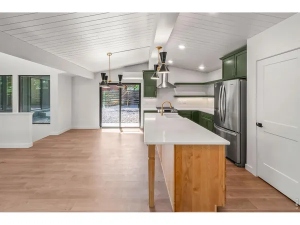 a kitchen with stainless steel appliances granite countertop a refrigerator a sink dishwasher a stove and a dining table with wooden cabinet