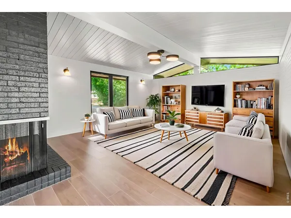 a view of an empty room with wooden floor and a fireplace
