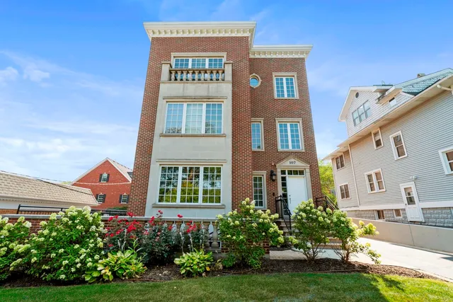a front view of a multi story residential apartment building with yard and flowers around