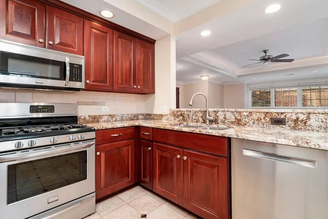 a kitchen with stainless steel appliances granite countertop wooden cabinets and a stove top oven