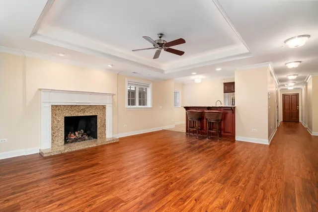 a view of a livingroom with a fireplace a ceiling fan and wooden floor