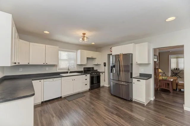 a kitchen with granite countertop stainless steel appliances a refrigerator a stove top oven and wooden floors