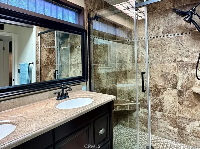 a bathroom with a granite countertop sink a mirror and shower