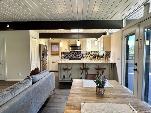 a living room with stainless steel appliances kitchen island furniture a rug and a kitchen