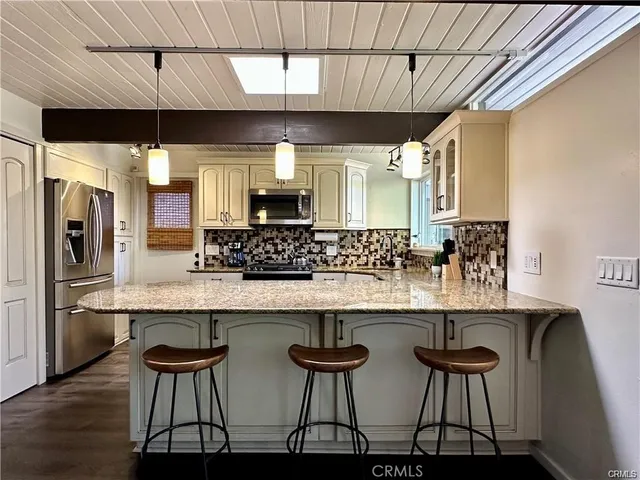 a kitchen with stainless steel appliances a dining table chairs microwave and sink