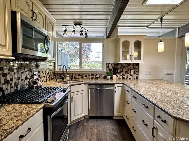 a kitchen with stainless steel appliances granite countertop a stove a sink and a microwave