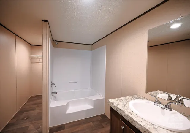 a bathroom with a granite countertop sink a mirror and a bathtub