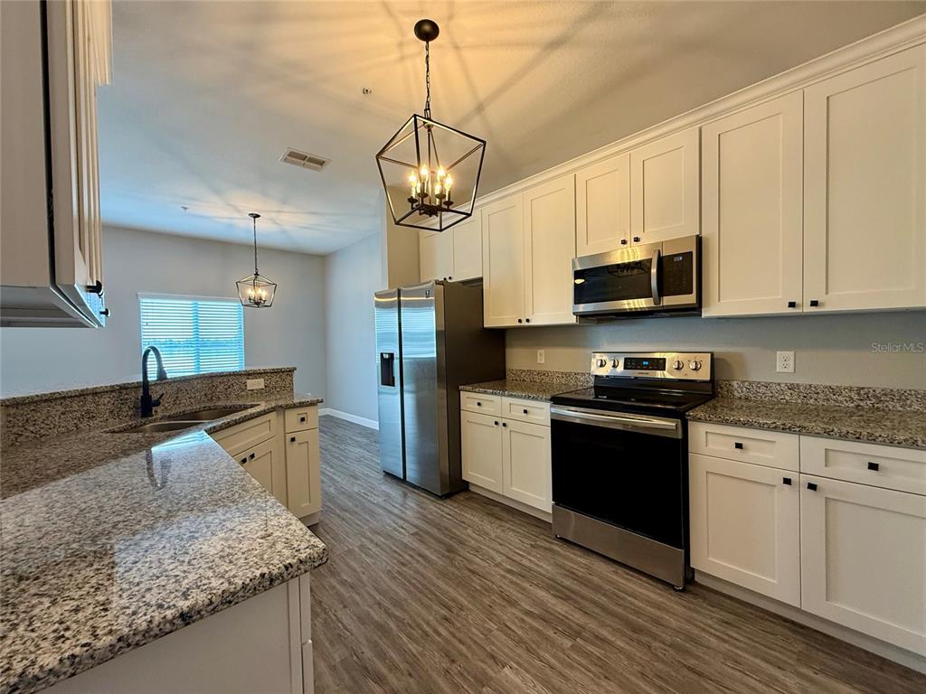 2653 Pine Place Winter Haven, FL 33881 - Photo 15 of 33 a kitchen with stainless steel appliances granite countertop a sink a stove top oven a counter space and cabinets