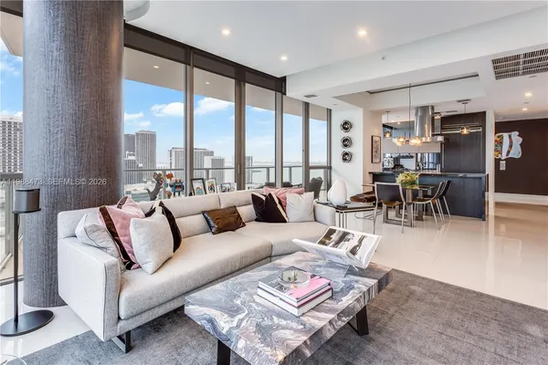 a living room with furniture kitchen view and a large window