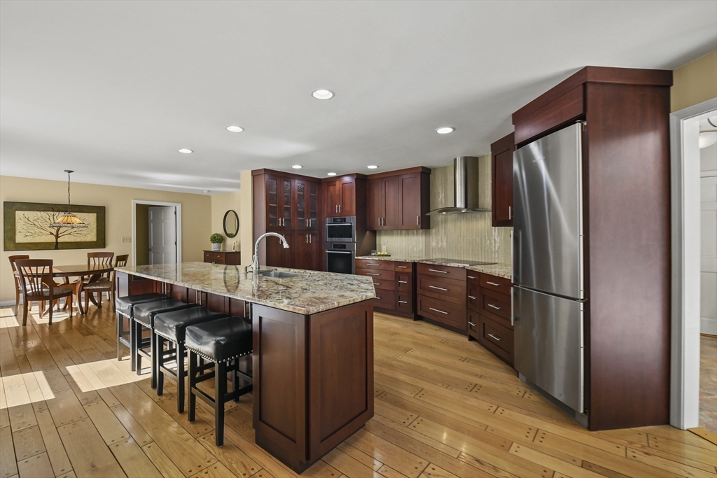 55 Prospect Hill Road Harvard, MA 01451 - Photo 10 of 42 a kitchen with stainless steel appliances granite countertop a refrigerator a stove a sink a dining table and chairs with wooden floor