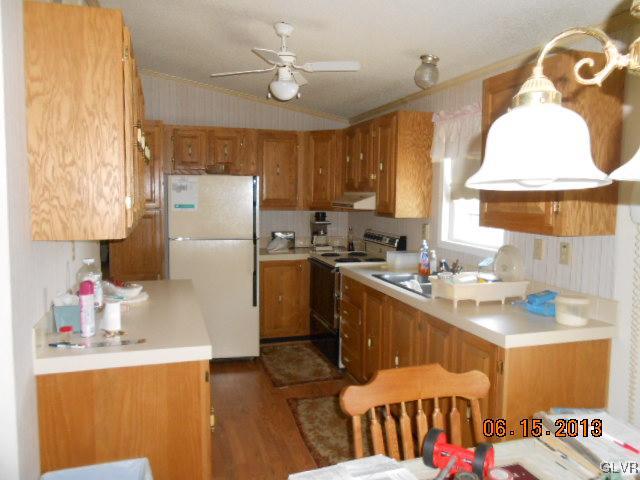 124 Rolling View Road Palmerton, PA 18071 - Photo 6 of 15 a kitchen with a refrigerator a sink dishwasher and a dining table with wooden cabinet