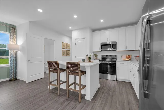 a kitchen with stainless steel appliances a dining table chairs stove refrigerator and microwave